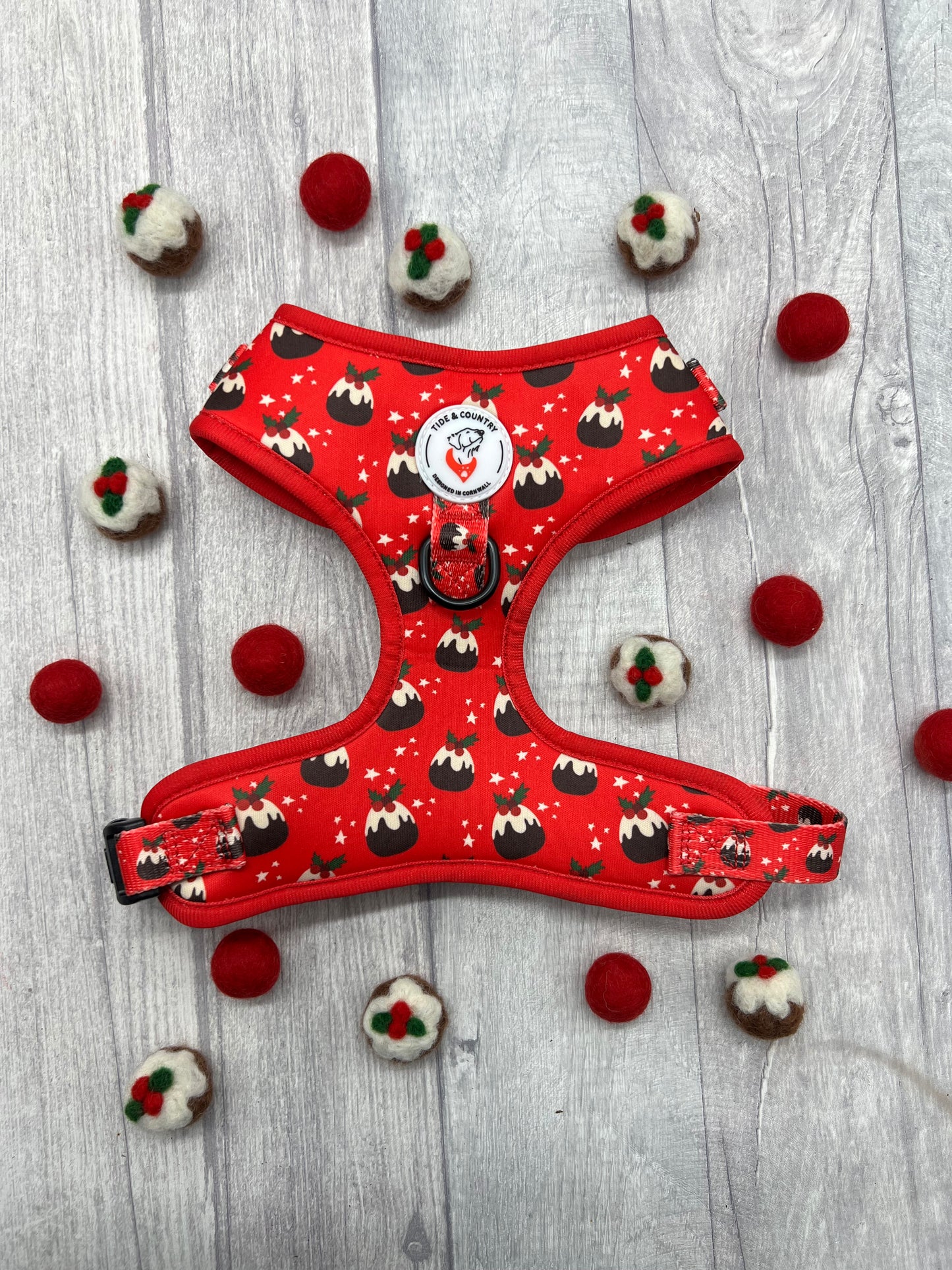 Red dog harness with Christmas puddings print, surrounded buy knitted red and christmas pudding balls