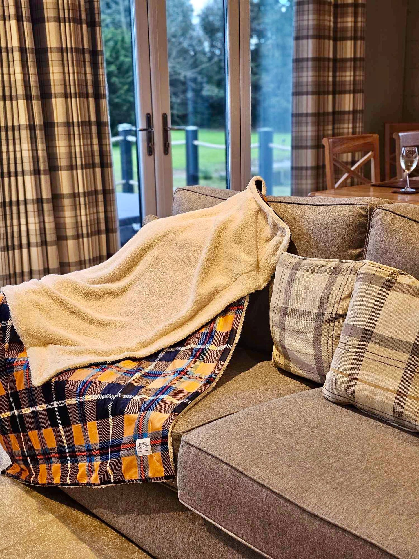Yellow Cornish Tartan Dog Throw with soft underside visible on a brown sofa